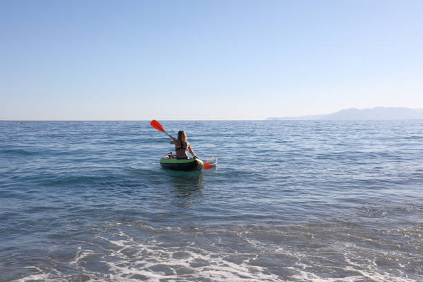 istock Woman pilots kayak from beach, into clear Mediterranean 1063628644