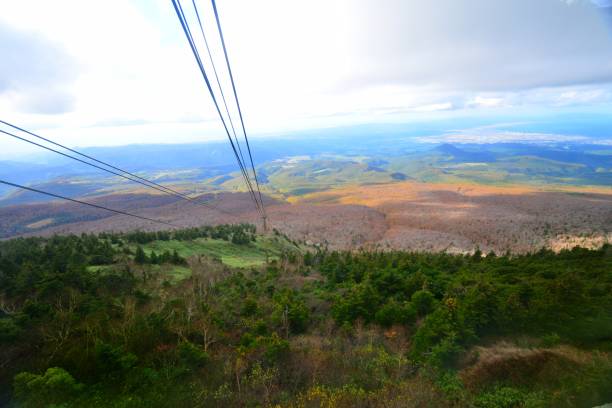 Autumn Colors and View from Hakkoda Summit Park, Aomori Prefecture Ten minutes ride in the gondola takes you to  Hakkoda Summit Park, which is located at the peak of Mt. Tamoyachi-dake, 1324 meters high. The park as well as the gondola ride commands an excellent panoramic view of the Hakkoda Mountains, Aomori City and Mutsu Bay, Tsugaru Peninsula, Shimokita Peninsula and Mt. Iwaki. 
You can enjoy beautiful autumn leaf colors as well as fresh greenery of early summer. You can also enjoy ski and snow trekking in winter. hakkoda mountain range stock pictures, royalty-free photos & images