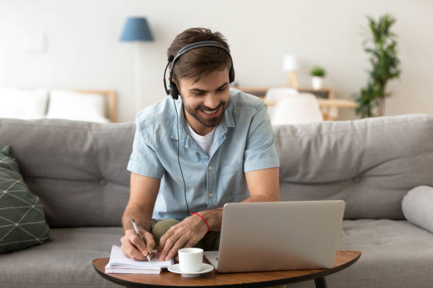 homme étudie l’écoute audio faisant quelques notes - living room learning healthy lifestyle one person photos et images de collection