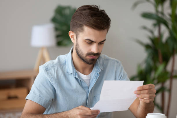 istock Head shot serious man reading letter sitting at home 1063637460