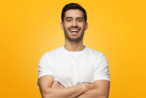 istock Young handsome man isolated on yellow background, with arms crossed, showing open friendly happy friendly smile 1063638568