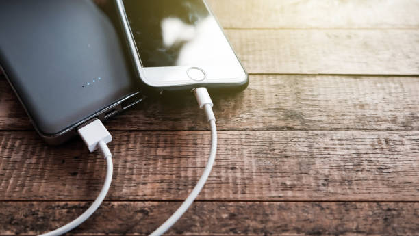 Mobile phone connect to power bank. Mobile phone connect to power bank on top view wooden desk. phone charger cable stock pictures, royalty-free photos & images