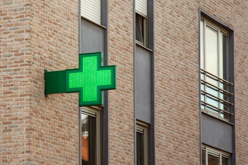 Green neon cross, symbol for a pharmacy store.