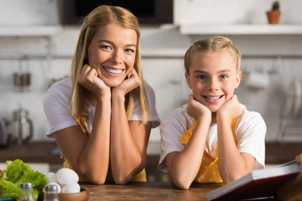 istock happy mother and daughter smiling at camera in kitchen 1063647226