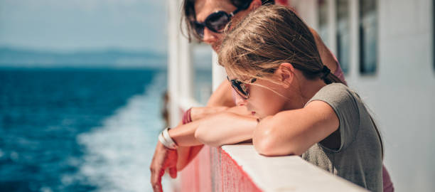 Mother and daughter traveling on a ferry boat Mother and daughter traveling on a ferry boat and standing on a ship deck on a sunny day ferry deck girls stock pictures, royalty-free photos & images