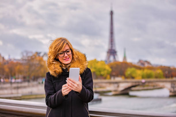 istock Girl using cellphone with Paris city background and Eiffel tower. 1063652042