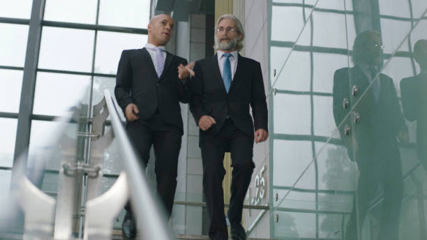 istock corporate executives talking while descending stairs in office building 1063652348