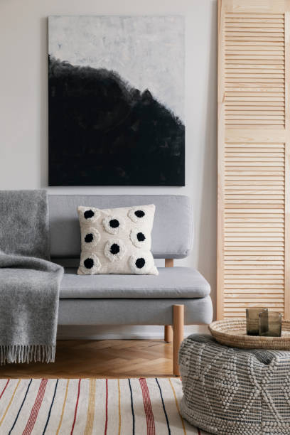 istock Poster above grey settee with patterned cushion and blanket in natural living room interior. Real photo 1063654814