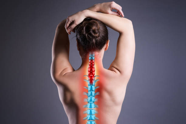 Pain in the spine, woman with backache on gray background, back injury Pain in the spine, woman with backache on gray background, back injury, photo with highlighted skeleton cervical vertebrae photos stock pictures, royalty-free photos & images