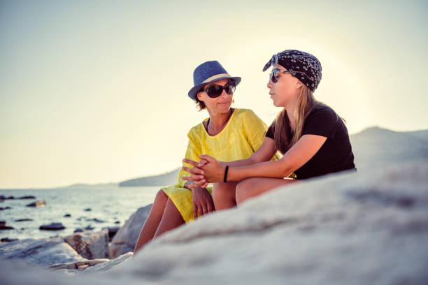 istock Mother and daughter talking on a rocky beach 1063665264