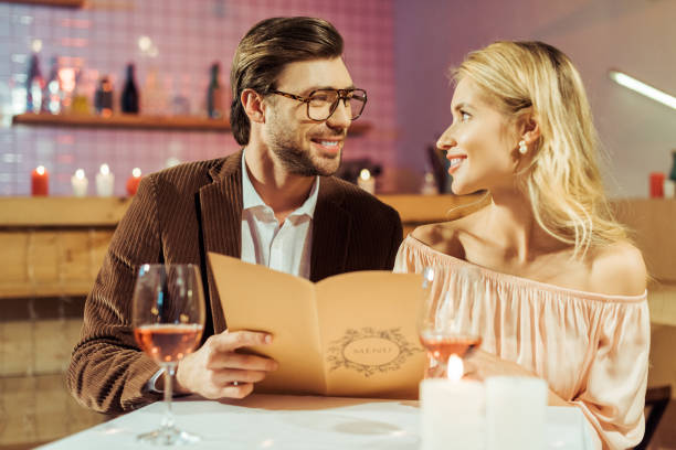 istock smiling couple with menu looking at each other during romantic dinner in restaurant 1063665900