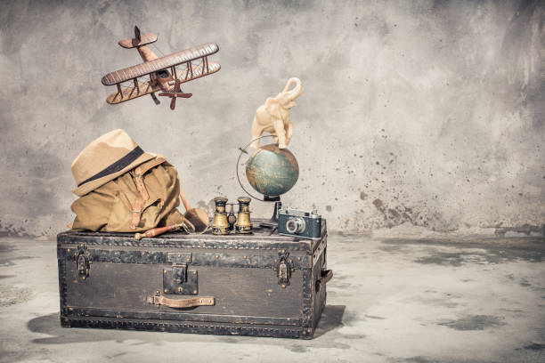 vintage old classic travel trunk luggage, flying wooden toy plane, elephant on aged globe, tourist backpack, hat, binoculars, film camera, magnifier. travel by air concept. retro style filtered photo - trunk luggage old fashioned retro revival imagens e fotografias de stock