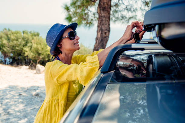 mujer abre la caja de carga en el portaequipajes en la playa - parasol pine fotografías e imágenes de stock