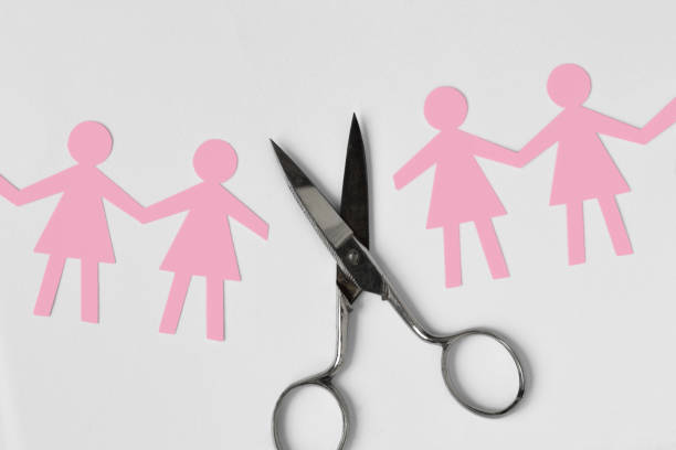 Broken women paper chain with scissors on white background - Broken relationships between woman concept stock photo