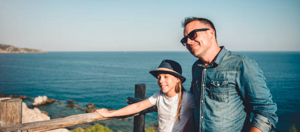 istock Father and daughter relaxing together by sea 1063673486