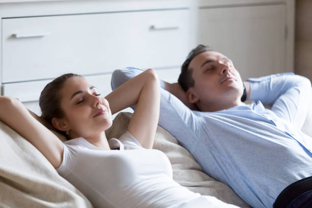 istock Man and woman lying on sofa relaxing with eyes closed 1063676566