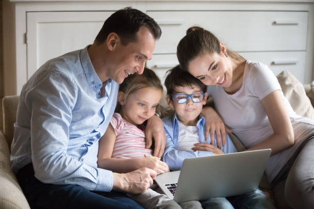 istock Parents cuddle with small kids watching cartoon on laptop 1063676568