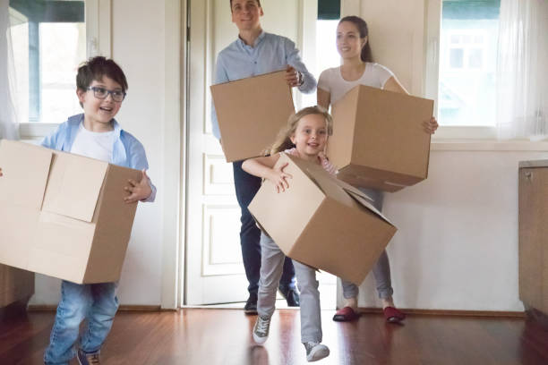 istock Excited kids running carrying boxes moving to new house 1063676732