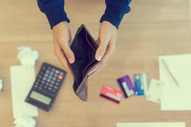 nahaufnahme der hand des menschen öffnen, leere brieftasche über rechner, schulden kosten monatlich rechnungen und kreditkarte am tisch im home-office, lohn-und gehaltsliste, risiko-finanzkonzept geld verwalten - bankrott stock-fotos und bilder