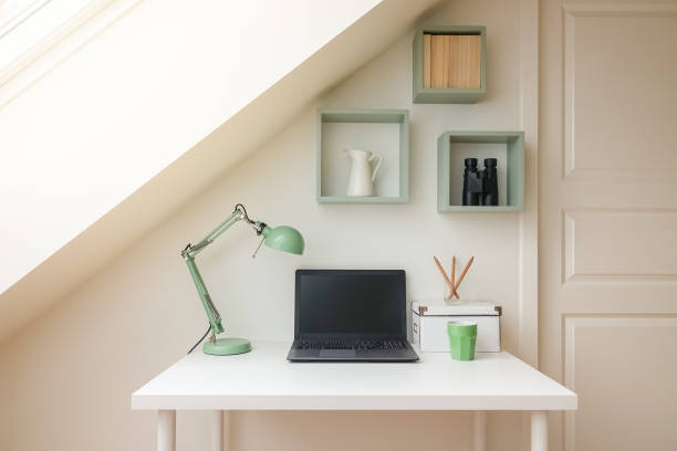 Modern workspace interior in cozy attic / loft apartment with skylight window letting the sun shine in.