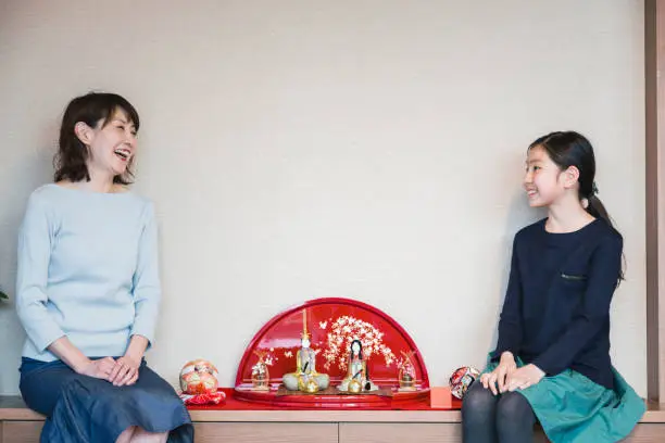Japanese mother and daughter sitting by Hina doll which is a Japanese doll displayed at the Girls' Festival.