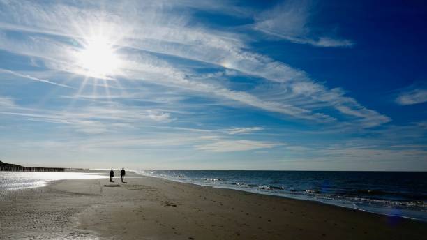istock Two persons walking at a lonely beach at sunset 1063688854