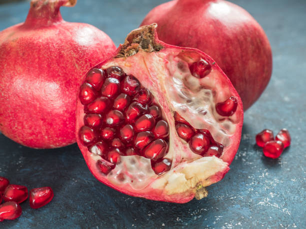 istock Fresh ripe red pomegranate fruit on a dark blue rustic background. Healthy food, closeup, flat lay, top view 1063701530