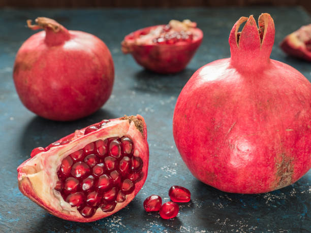 istock Fresh ripe red pomegranate fruit on a dark blue rustic background. Healthy food, closeup, flat lay, top view 1063701552