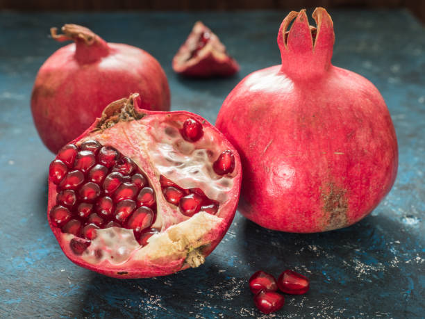 istock Fresh ripe red pomegranate fruit on a dark blue rustic background. Healthy food, closeup, flat lay, top view 1063701574