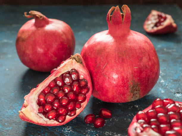 istock Fresh ripe red pomegranate fruit on a dark blue rustic background. Healthy food, closeup, flat lay, top view 1063701582