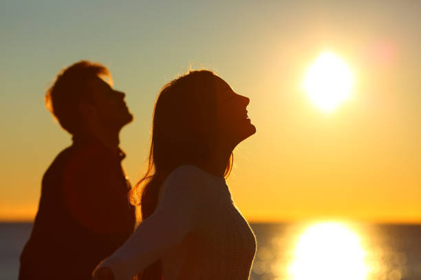 silhouette d’un couple d’amis respirent au coucher du soleil - family beach cheerful happiness photos et images de collection