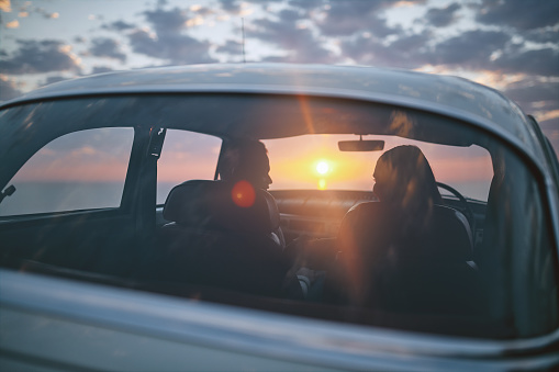 Rearview shot of a couple stopping to watch the sunset while on a road trip