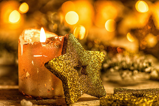 goldenere weihnachtsstern mit tannenzweig, kerze und lichtern im hintergrund - essen und photos et images de collection