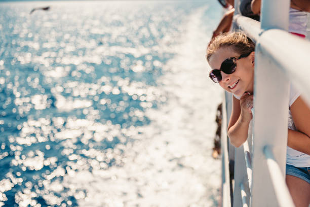 Girl standing on a ship deck at ferry Girl wearing sunglasses standing at ship deck on a ferryboat and looking at the sea ferry deck girls stock pictures, royalty-free photos & images