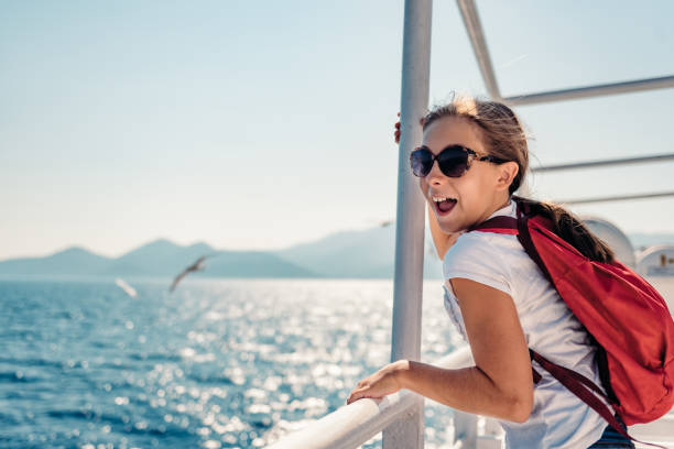 Girl standing on a ship deck at ferry Girl wearing sunglasses standing at ship deck on a ferryboat and looking at the sea ferry deck girls stock pictures, royalty-free photos & images