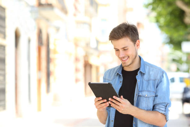 Happy man using a tablet standing in the street