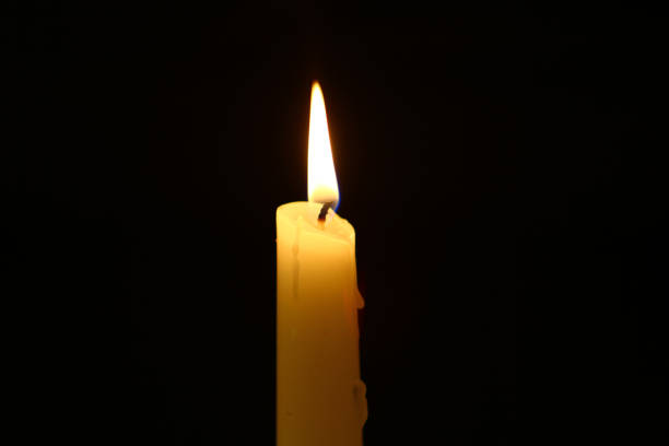 istock big wax lighting yellow candle with big flame on the dark background. 1063709616