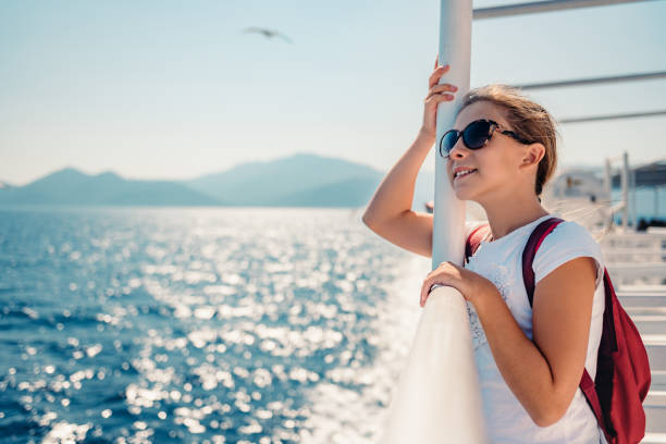 Girl standing on a ship deck at ferry Girl wearing sunglasses standing at ship deck on a ferryboat and looking at the sea ferry deck girls stock pictures, royalty-free photos & images