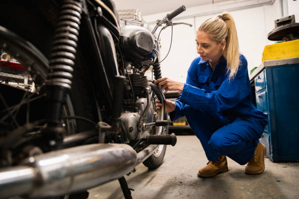 Woman Repairing Motorcycle A close-up shot of a woman repairing a motorcycle in a garage, she is working hard. role reversal stock pictures, royalty-free photos & images