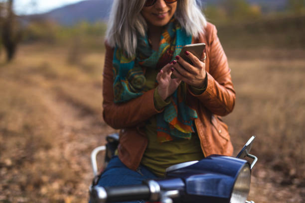 istock Female motorcycle driver typing on smart phone 1063712892