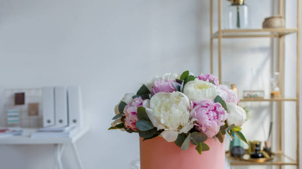 istock Flower delivery to the office. Working space, table with notebooks and magazines. A luxurious bouquet of peonies 1063713136