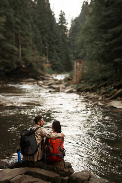 istock Romantic hiker looking at his girlfriend while hugging her near the river 1063714034