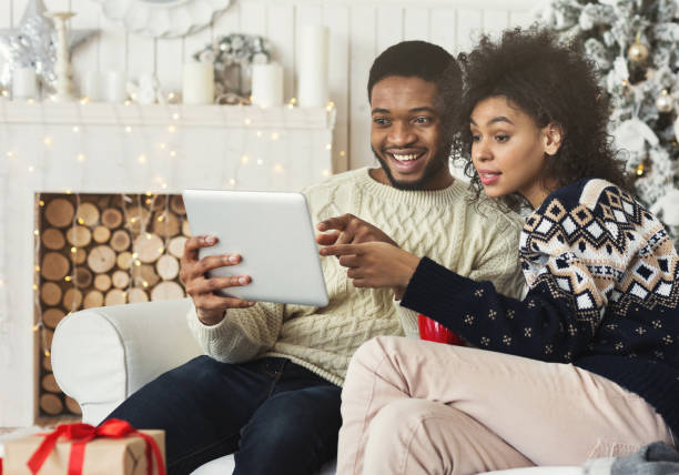 istock Young couple sitting in christmas decorated room and using table 1063715264