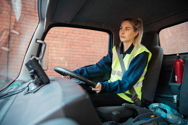 Manual Worker Driving to Work A close-up shot of a young female manual worker in a van driving to work. drivers seat stock pictures, royalty-free photos & images