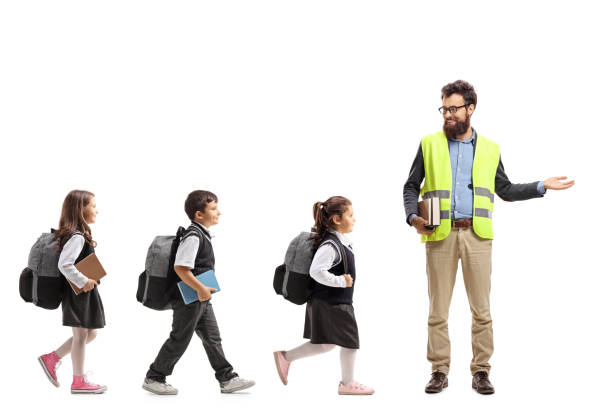 istock Schoolchildren walking in a line and a teacher gesturing with his hand 1063723680