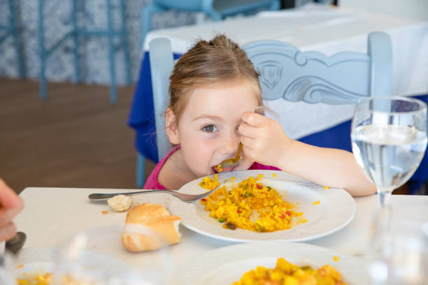 funny little girl eating paella and looking at you stock photo