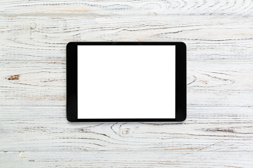 black digital tablet on rustic wooden table background. mock up top view.