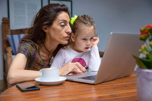 istock mother teaching her little daughter on laptop 1063727132