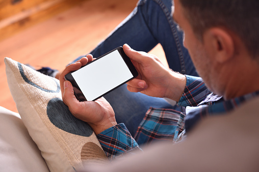Man sitting on sofa watching multimedia content on a smartphone
