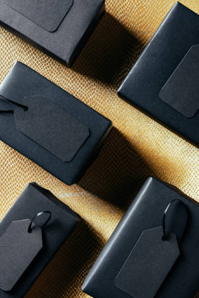 istock flat lay with black boxes with blank price tags on golden backdrop, black friday concept 1063735144